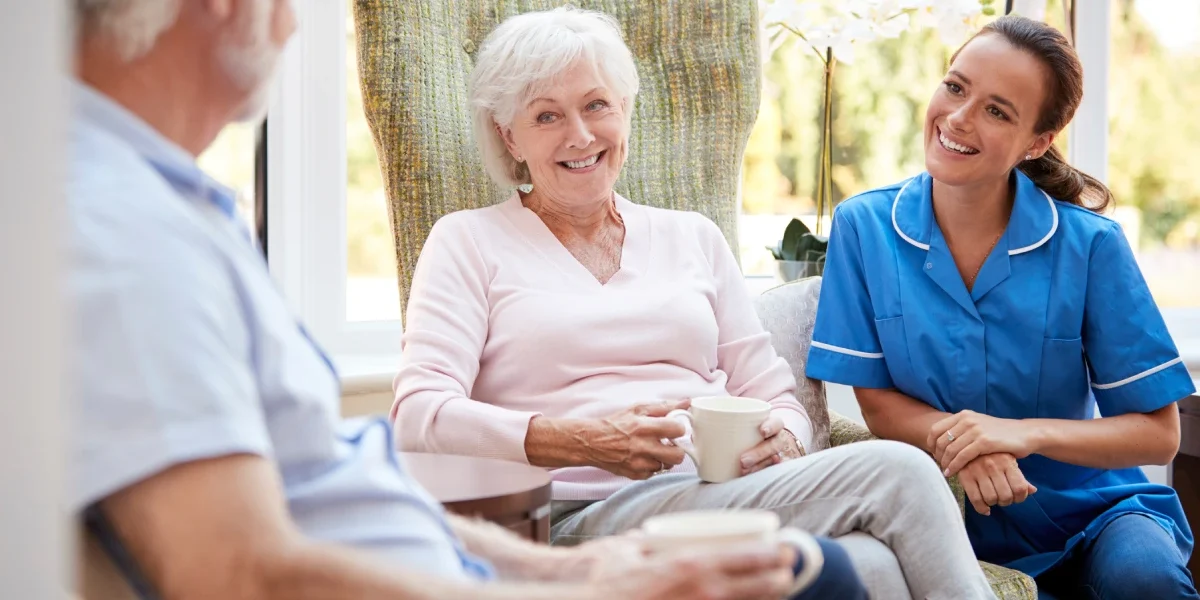 Seniors drinking coffee and talking with caregiver